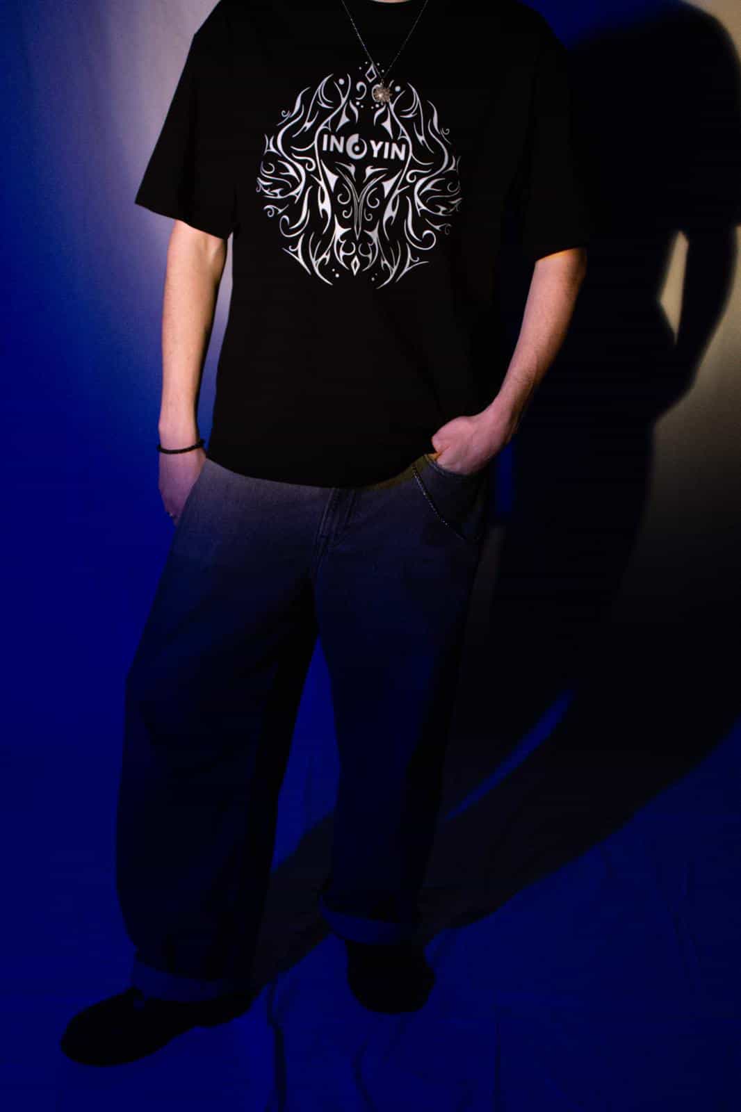 Ein Foto von Ino Yin und seinem Merch mit dem Motiv auf der Vorderseite und auf der Rückseite