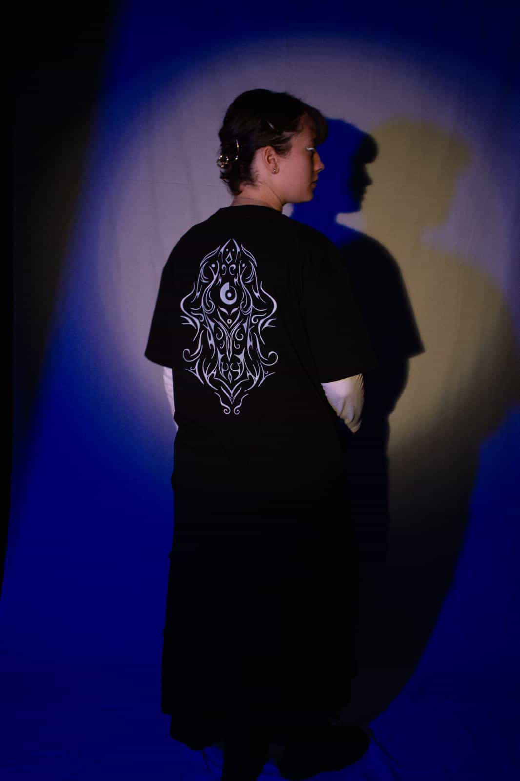Ein Foto von Ino Yin und seinem Merch mit dem Motiv auf der Vorderseite und auf der Rückseite